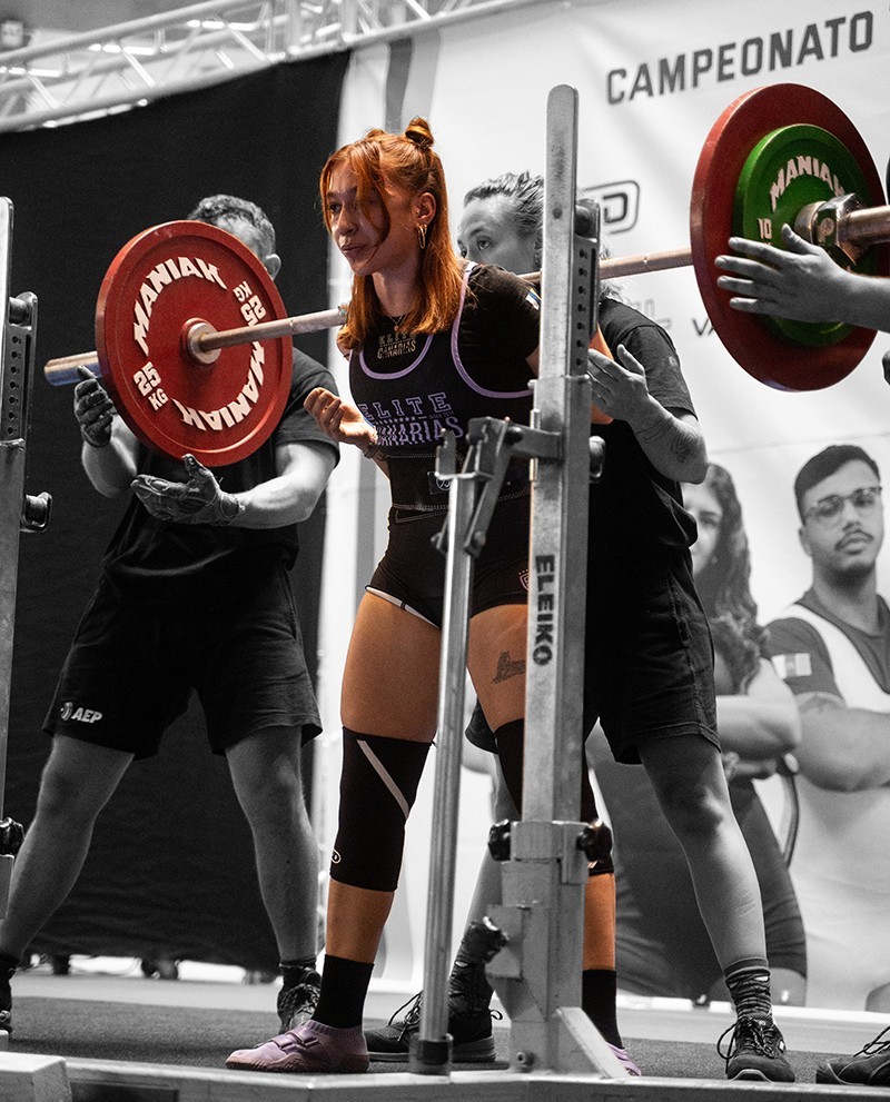 Chica powerlifter haciendo sentadilla